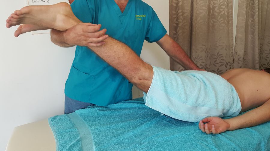 Therapist supporting a client's leg during a passive hamstring stretch